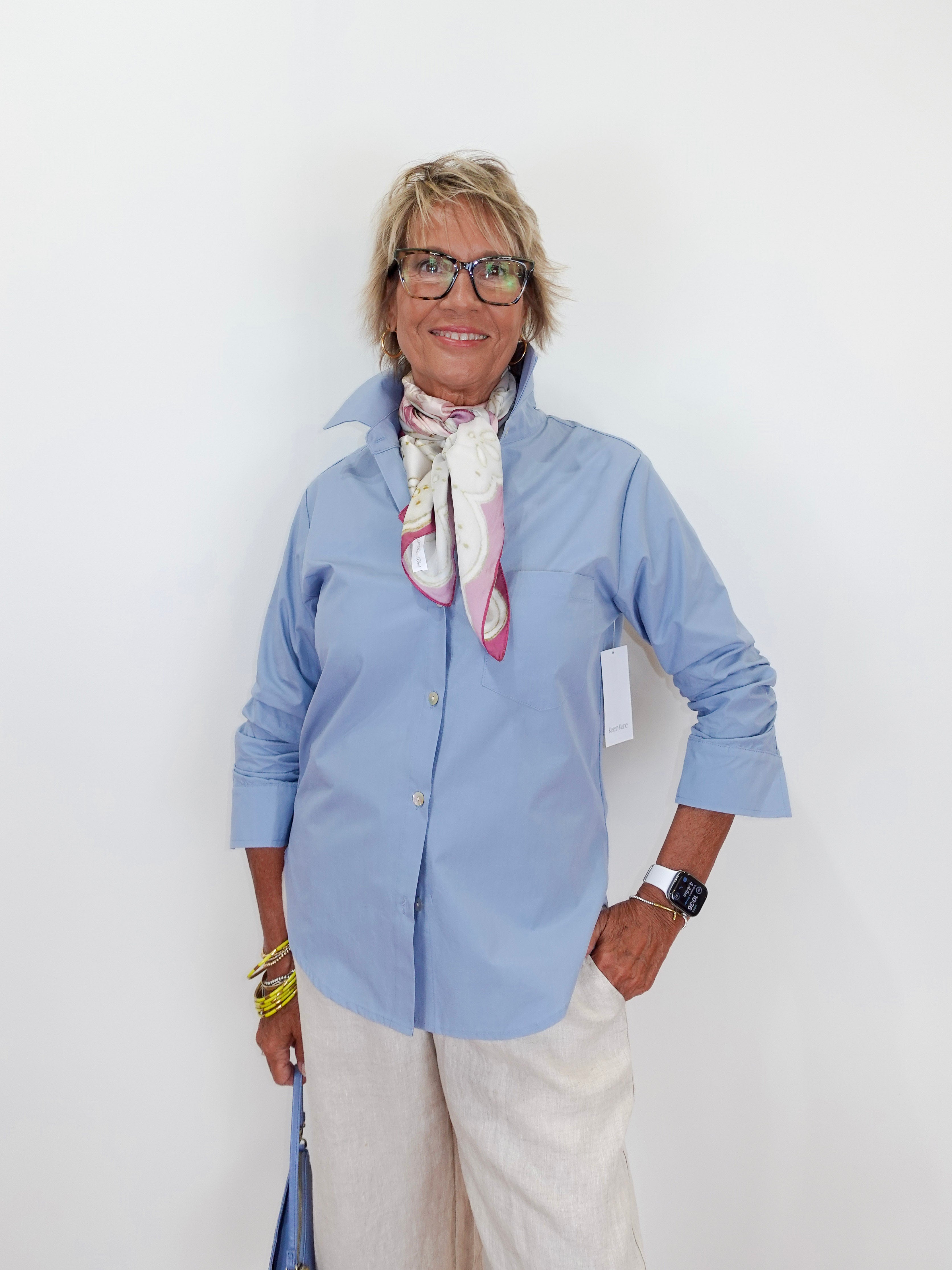 Woman wearing a light blue shirt and white pants against a white background