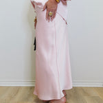 woman wearing a pink satin skirt against a white background. 