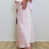 woman wearing a pink satin skirt against a white background. 
