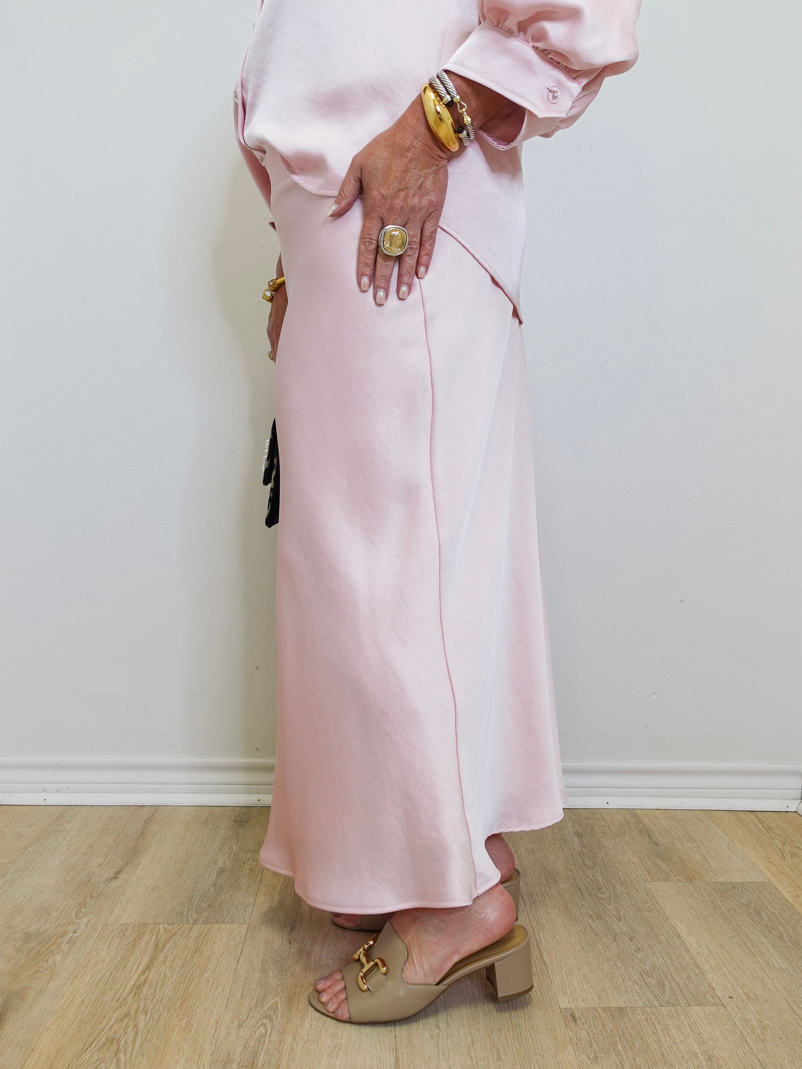 woman wearing a pink satin skirt against a white background. 