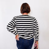 Person wearing a black and white striped sweater against a plain background