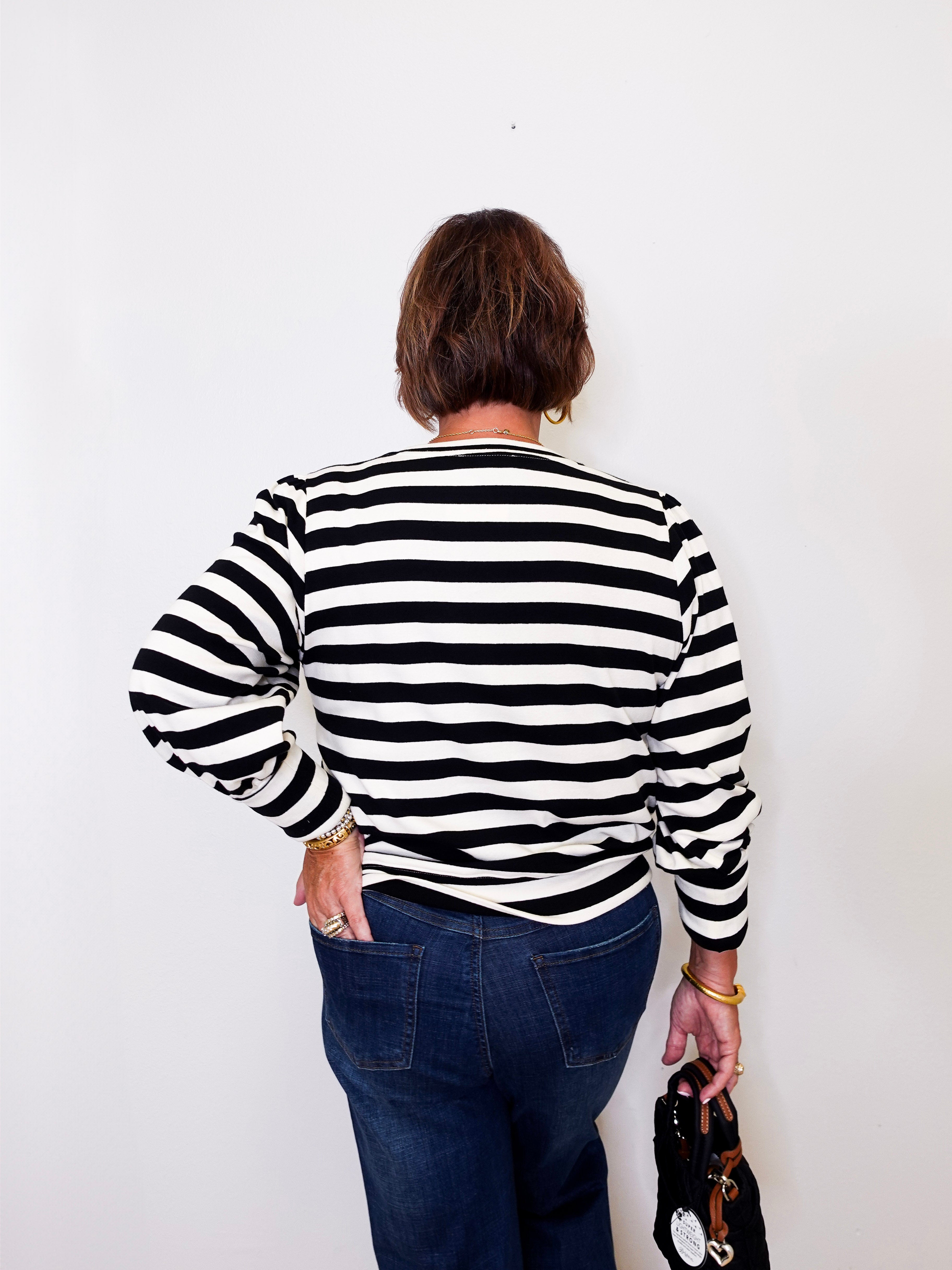 Person wearing a black and white striped sweater against a plain background