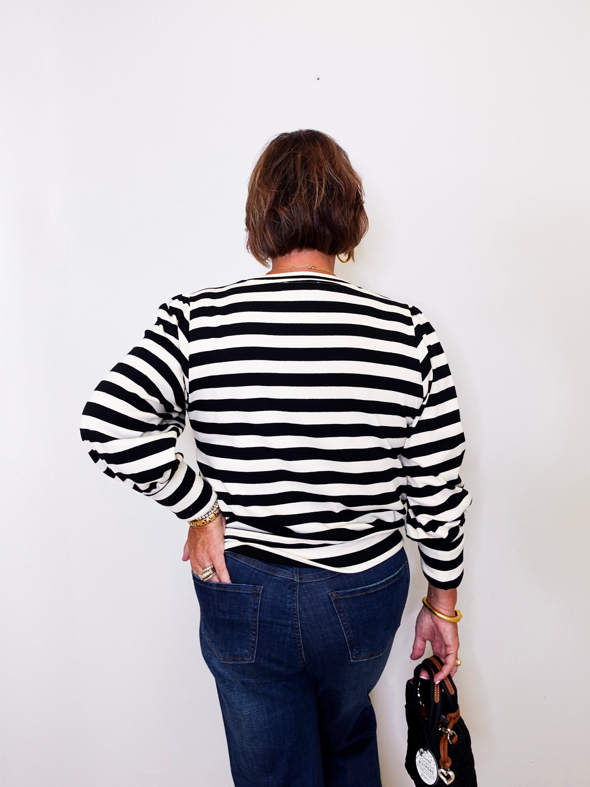 Person wearing a black and white striped sweater against a plain background