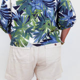 Person wearing a tropical leaf pattern shirt and beige shorts on a white background