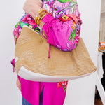 Person holding a straw bag with a colorful floral-patterned jacket