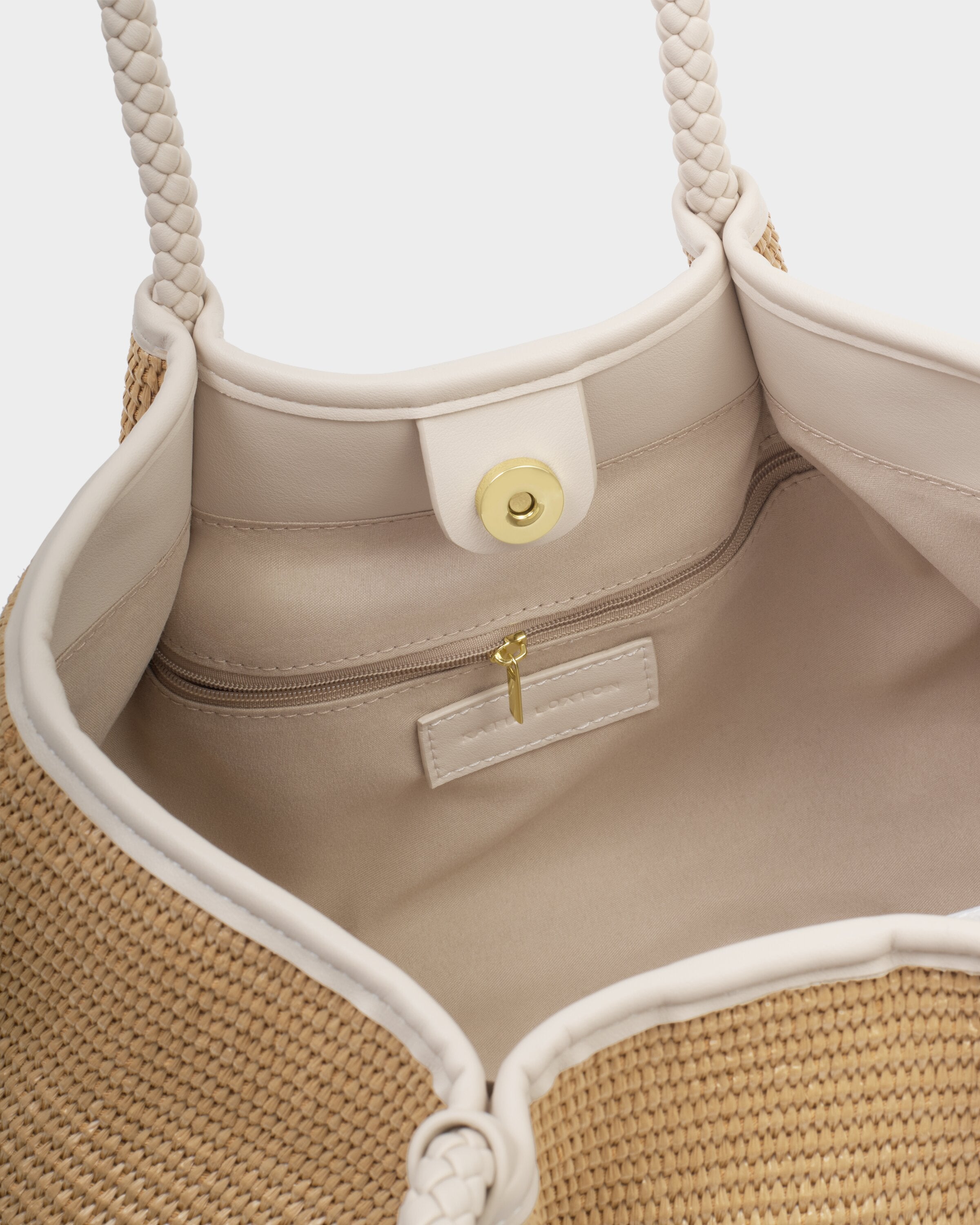 Close-up of a beige handbag with braided handle and interior details.