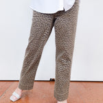 Person wearing leopard print pants and a white shirt on a white background