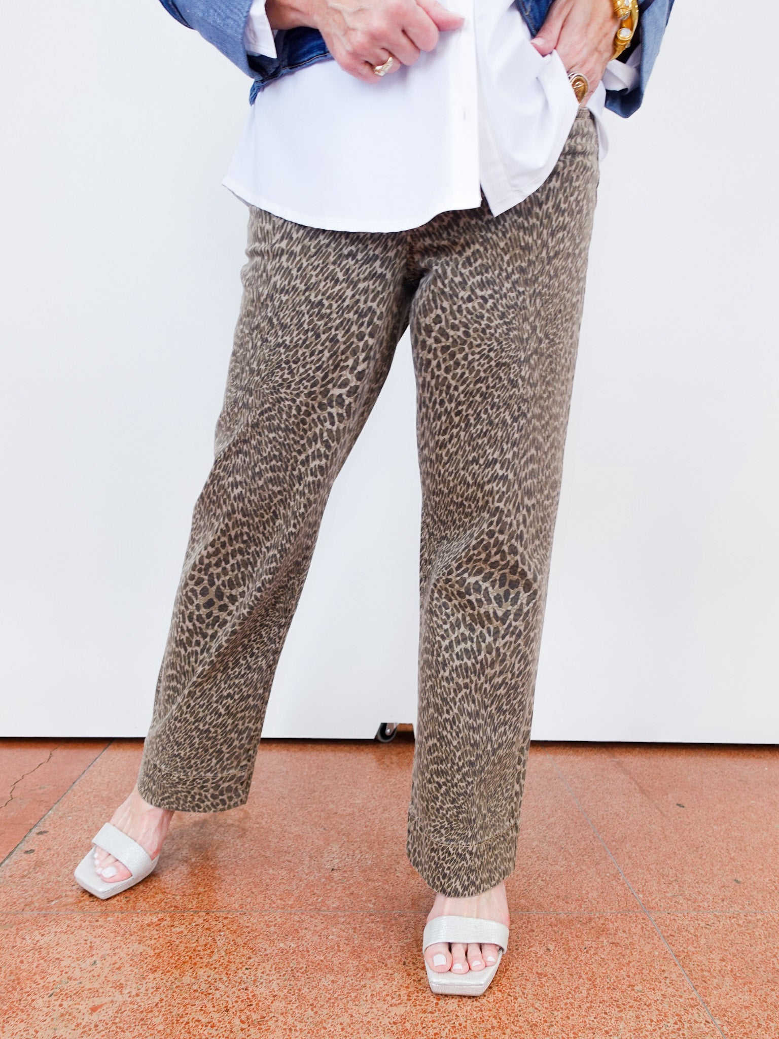 Person wearing leopard print pants and a white shirt on a white background
