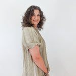 Woman wearing a light green blouse and beige pants against a white background