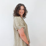 Woman wearing a light green blouse and beige pants against a white background