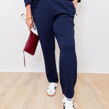 Person wearing navy tracksuit with white sneakers on a light wooden floor.