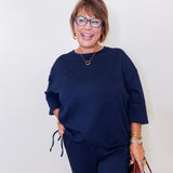 Woman wearing a navy blue outfit with glasses against a white background