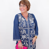 Woman wearing a blue floral dress with a pink clutch against a white background