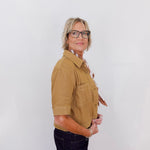 Person wearing a tan shirt and black pants against a white background