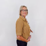 Person wearing a tan shirt and black pants against a white background