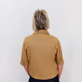 Person wearing a brown shirt and dark pants against a white background