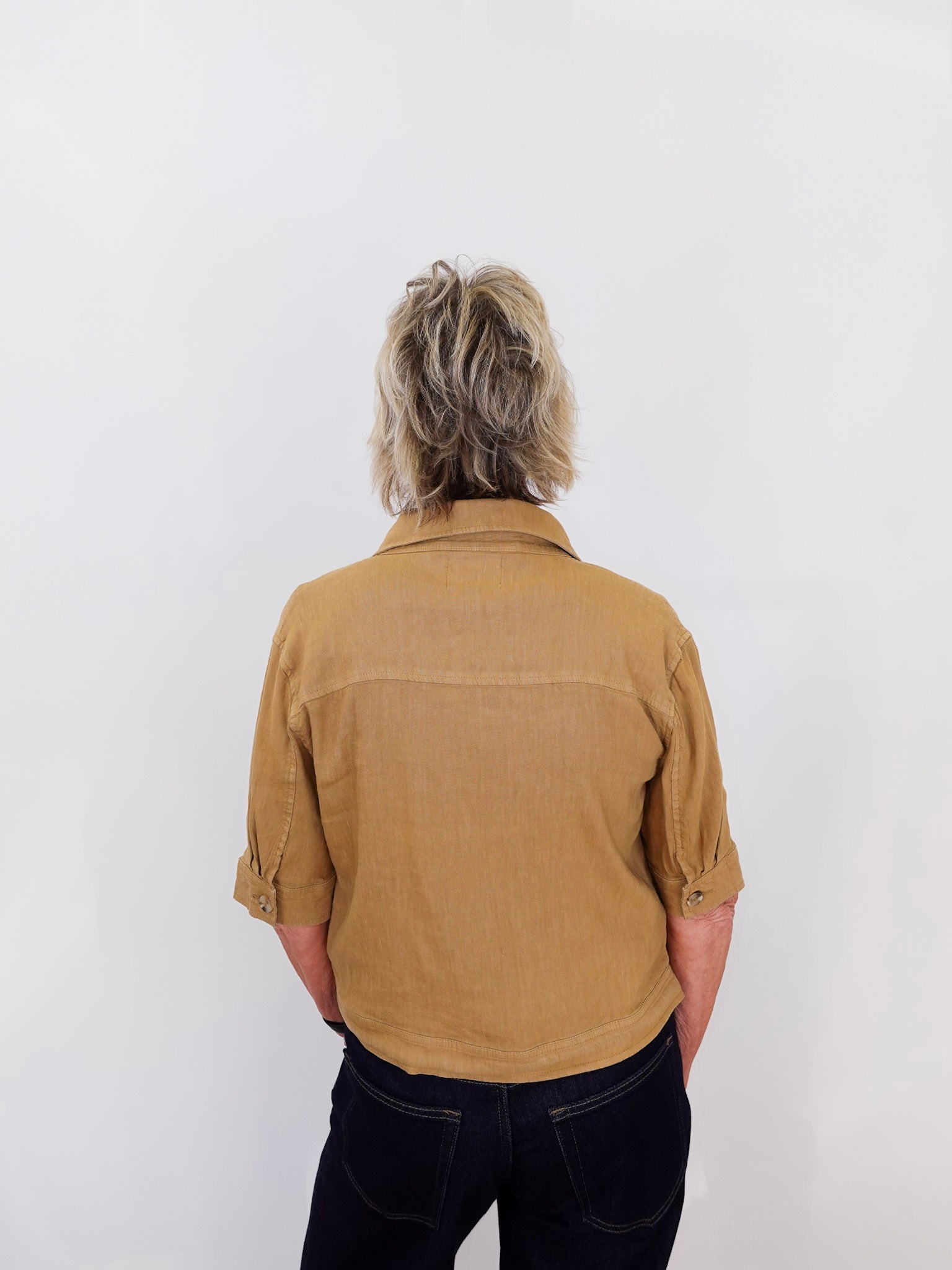 Person wearing a brown shirt and dark pants against a white background