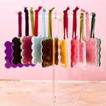 Colorful hair ties on a clear stand against a pink background