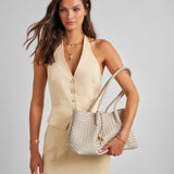 Woman holding a woven handbag against a plain background