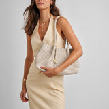 Woman holding a woven handbag against a plain background