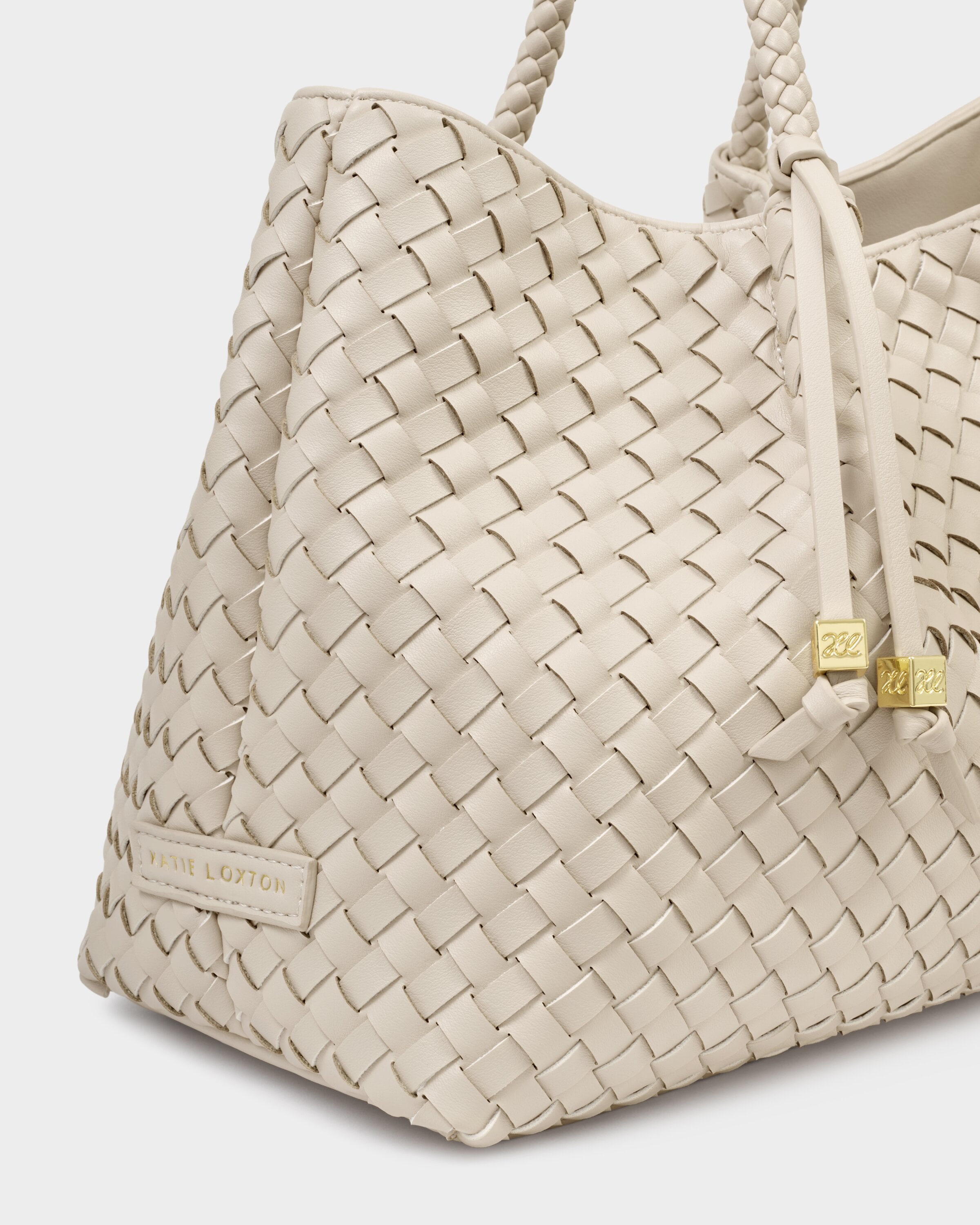 Beige woven handbag with a visible brand logo on a light gray background