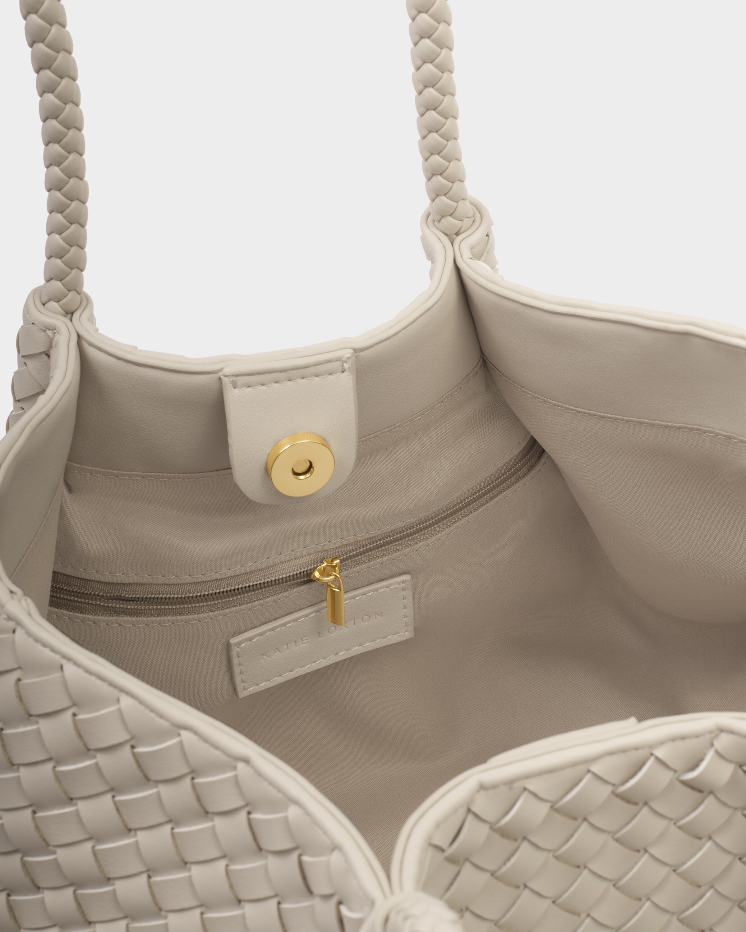 Close-up of a beige handbag with braided handles and woven pattern.