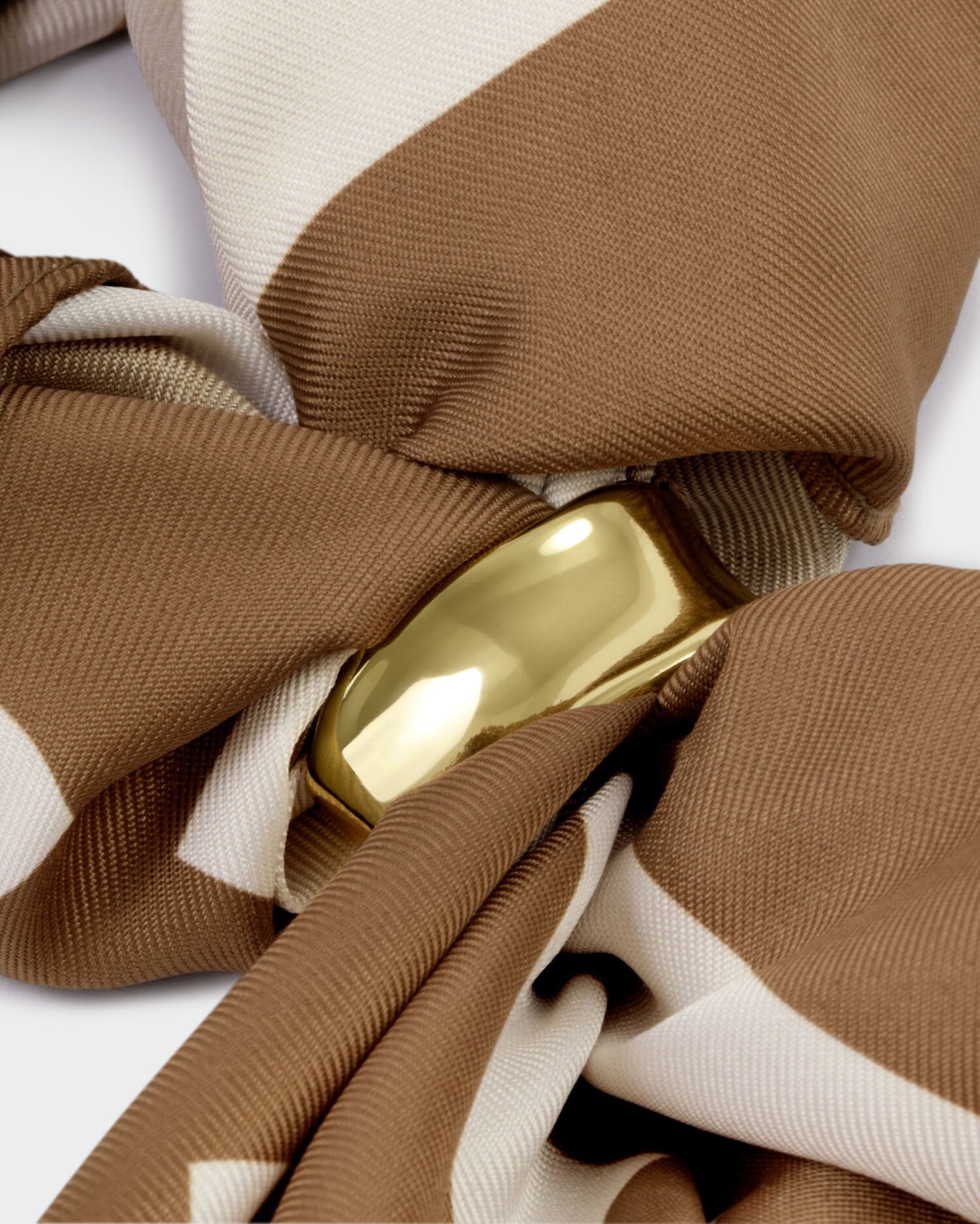 Close-up of a brown and beige fabric with a gold buckle on a white background