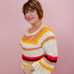 Woman wearing a colorful striped sweater against a pink background
