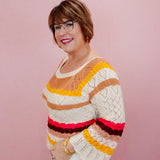 Woman wearing a colorful striped sweater against a pink background