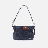 Navy blue handbag with a brown phone case on a light gray background