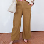 Person wearing brown wide-leg pants with a white background