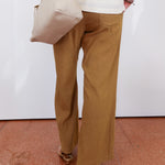 Person wearing beige pants and a white top, holding a beige handbag on a red and white floor.
