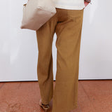 Person wearing beige pants and a white top, holding a beige handbag on a red and white floor.