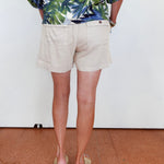 Person wearing a tropical print shirt and beige shorts on a plain background