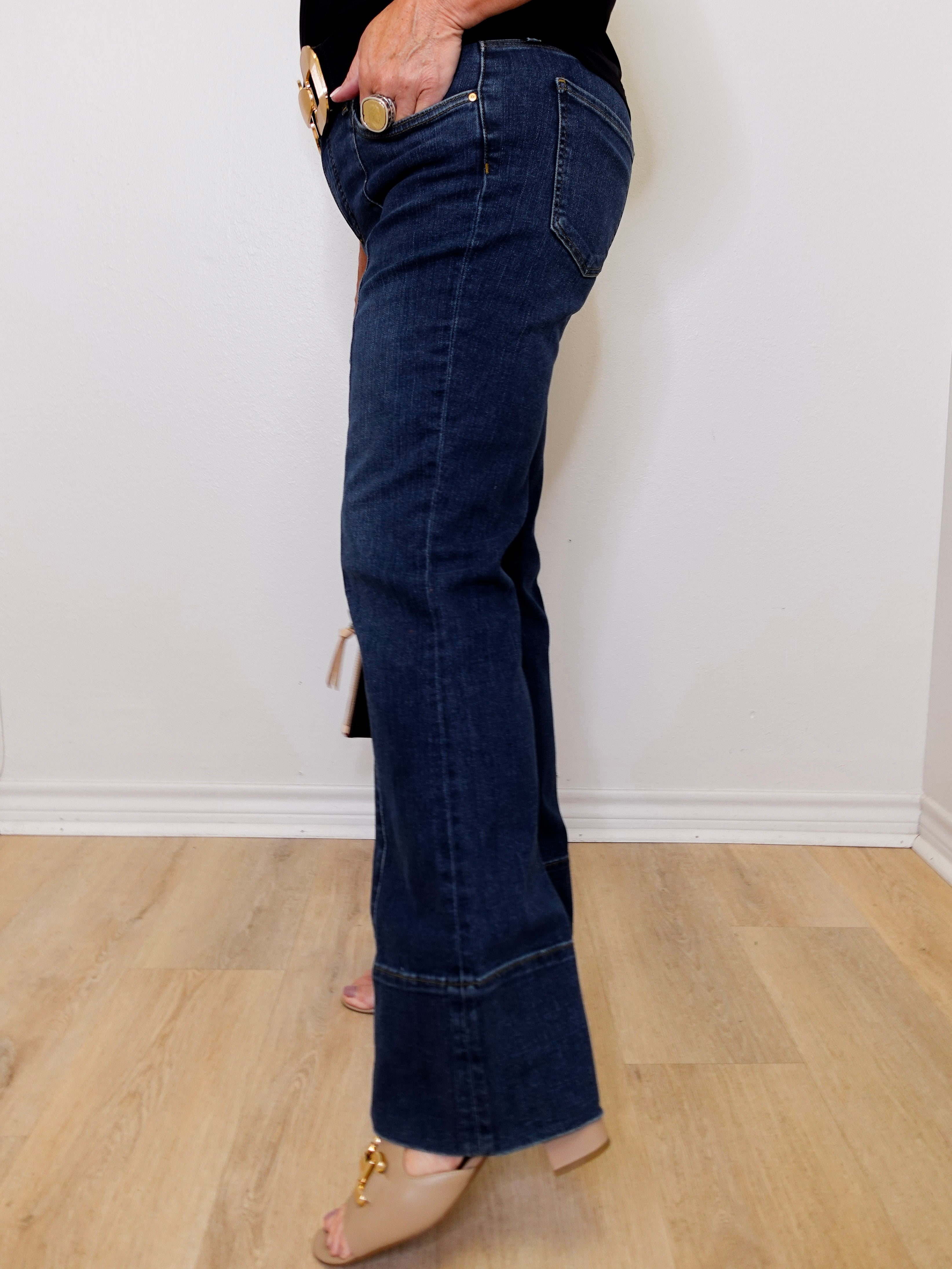 Person wearing blue jeans with a white wall background