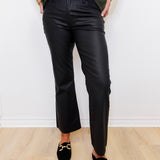 Person wearing black pants and green shirt against a white wall