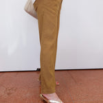 Person wearing mustard yellow pants and a white jacket with a plain background