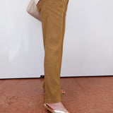 Person wearing mustard yellow pants and a white jacket with a plain background