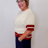 Woman wearing a white and red striped sweater against a plain background