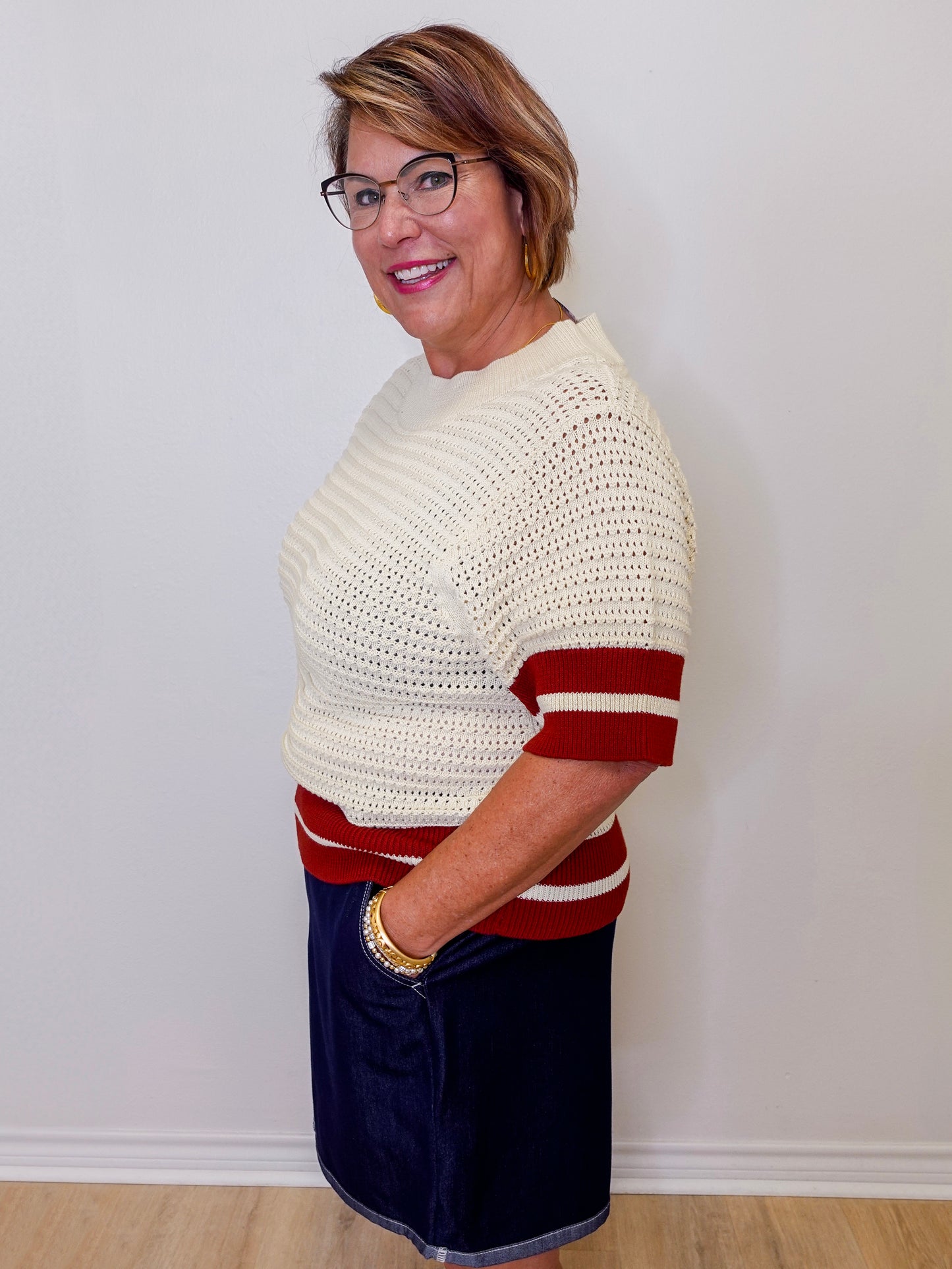 Woman wearing a white and red striped sweater against a plain background
