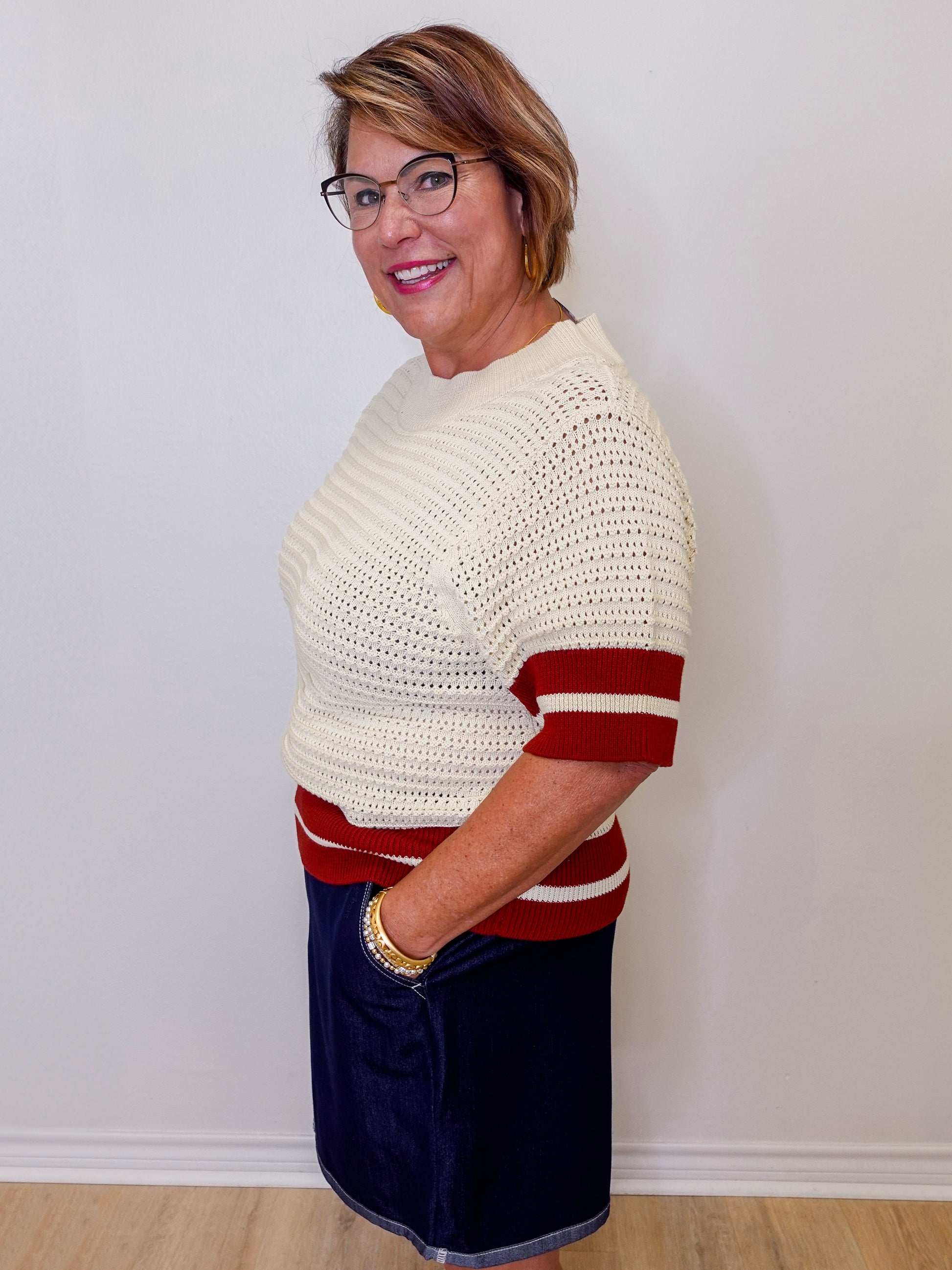 Woman wearing a white and red striped sweater against a plain background