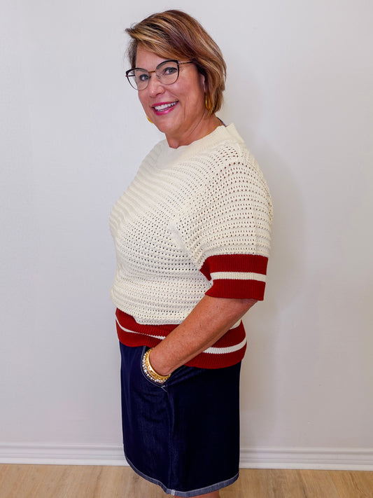 Woman wearing a white and red striped sweater against a plain background