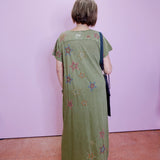 Person wearing a long green dress with star patterns against a plain background