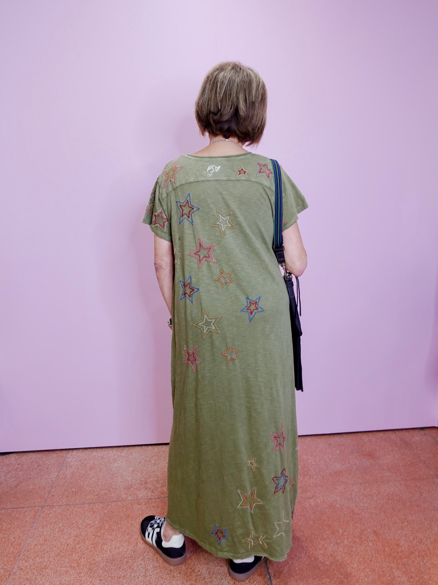 Person wearing a long green dress with star patterns against a plain background