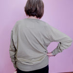 Person wearing a light green sweater against a pink wall