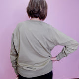 Person wearing a light green sweater against a pink wall