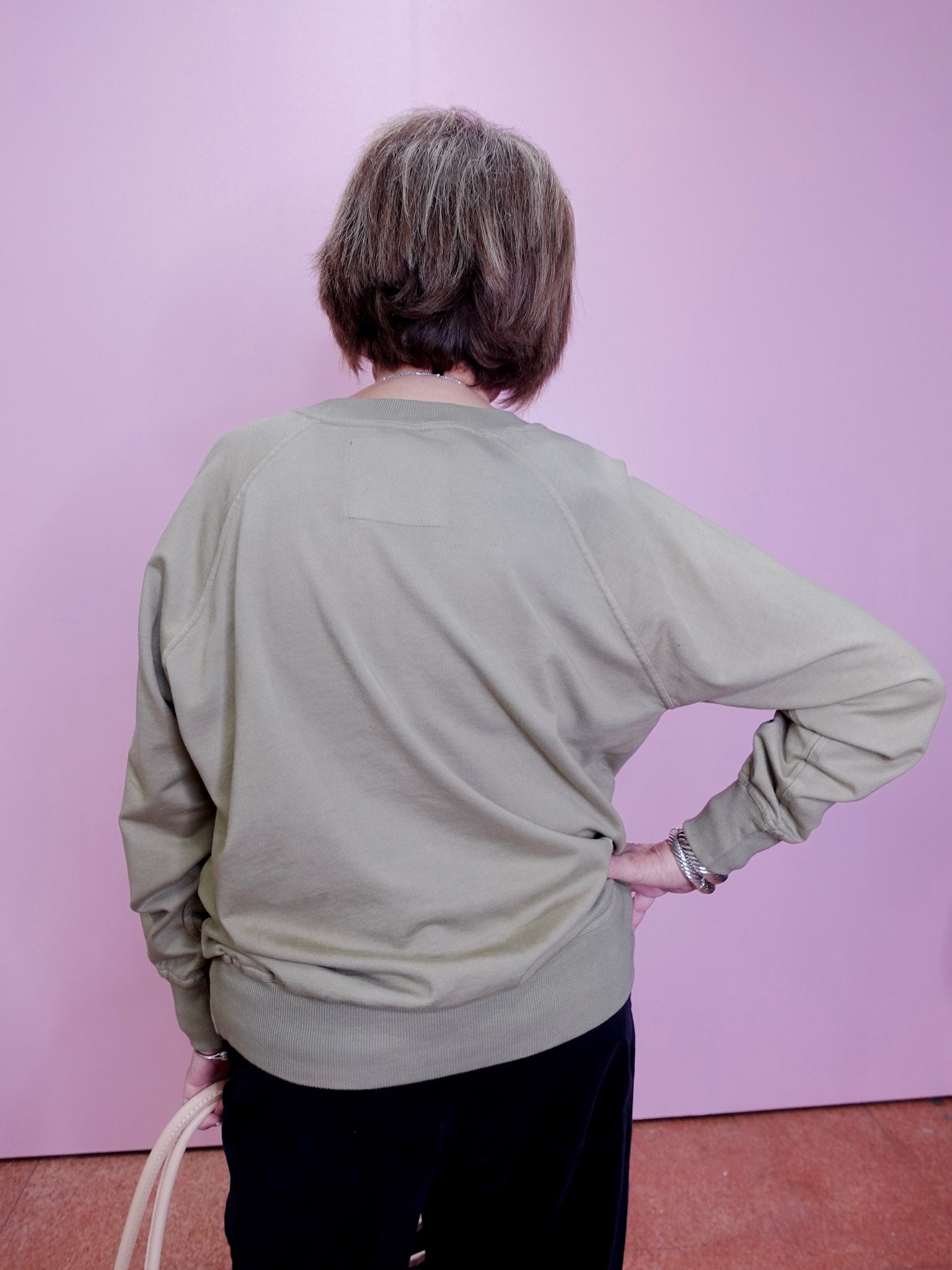 Person wearing a light green sweater against a pink wall
