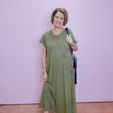 Woman wearing a green dress with floral patterns against a plain background