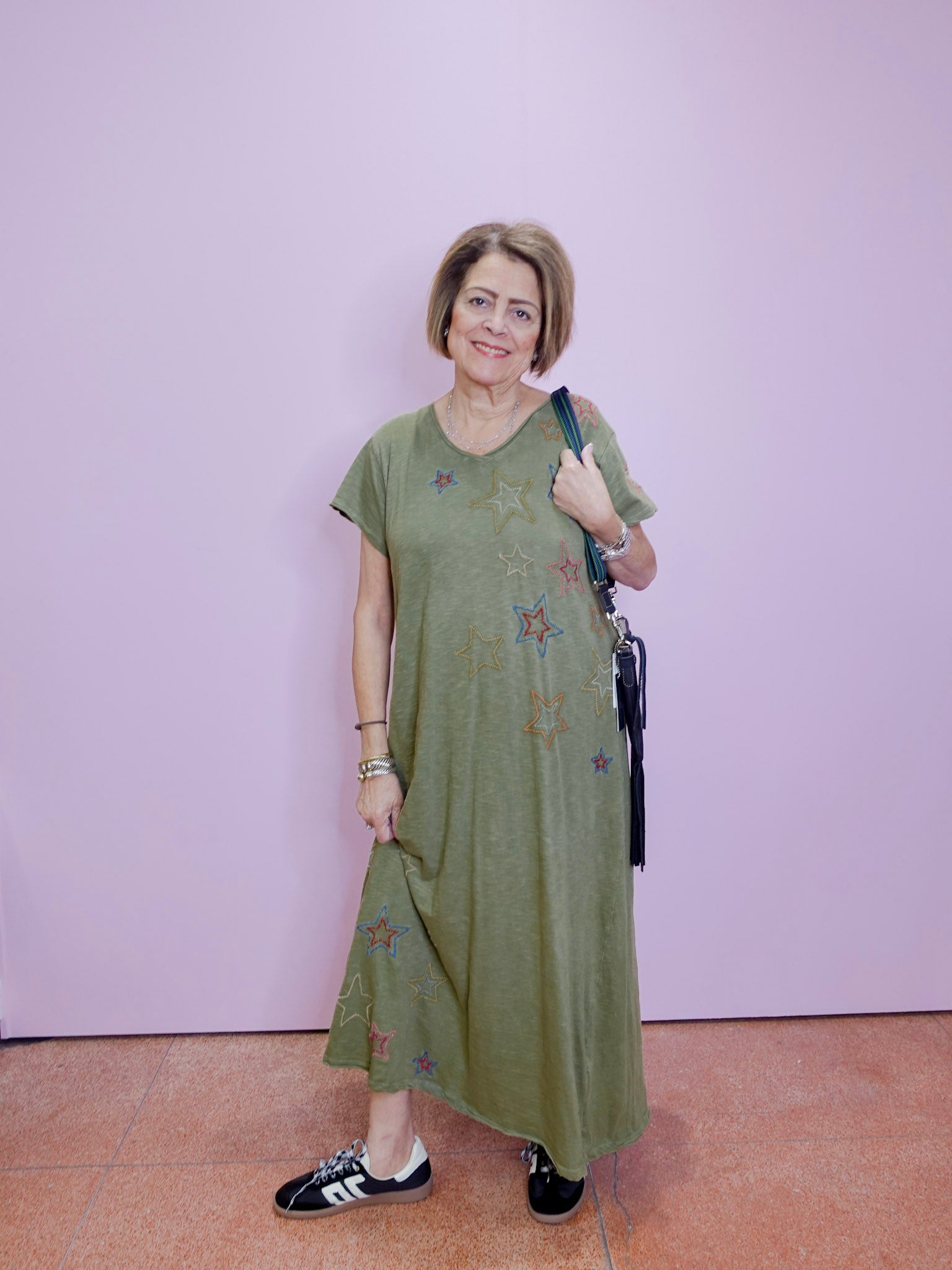 Woman wearing a green dress with floral patterns against a plain background