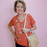 Woman holding a beige handbag against a pink wall